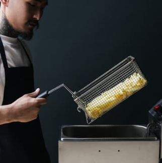 Seseorang menggunakan deep fryer untuk menggoreng